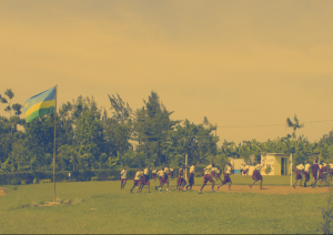 Pupils running in a circle in the school yard next to the Rwandan flag